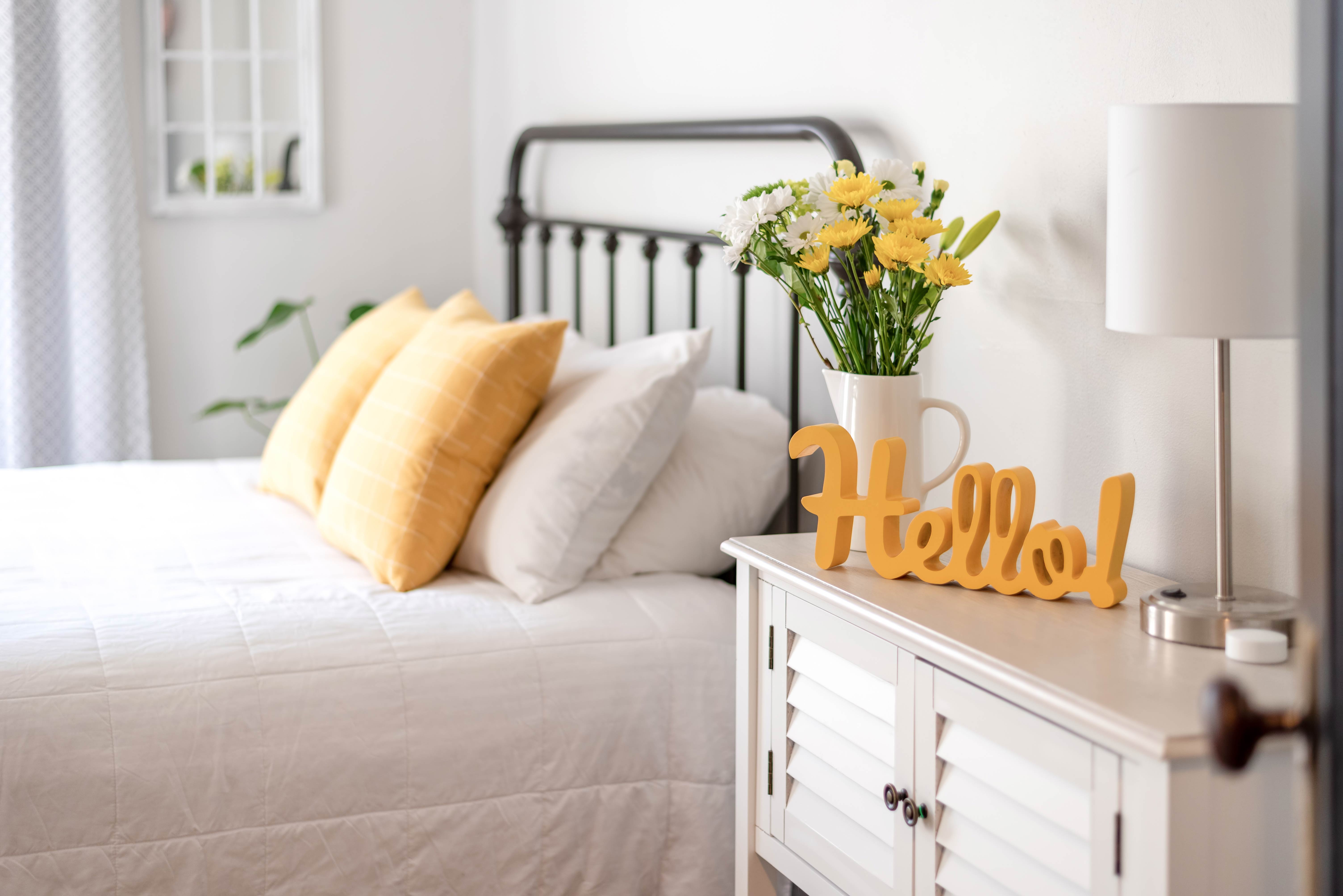 Cheerful-hello-sign-in-clean-and-bright-bedroom-with-yellow-accents.