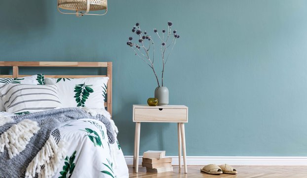 Minimalistic-composition-of-bedroom-interior-with-wooden-bed,-shelf,-flowers-in-vase,-rattan-lamp,-books-and-elegant-accessories
